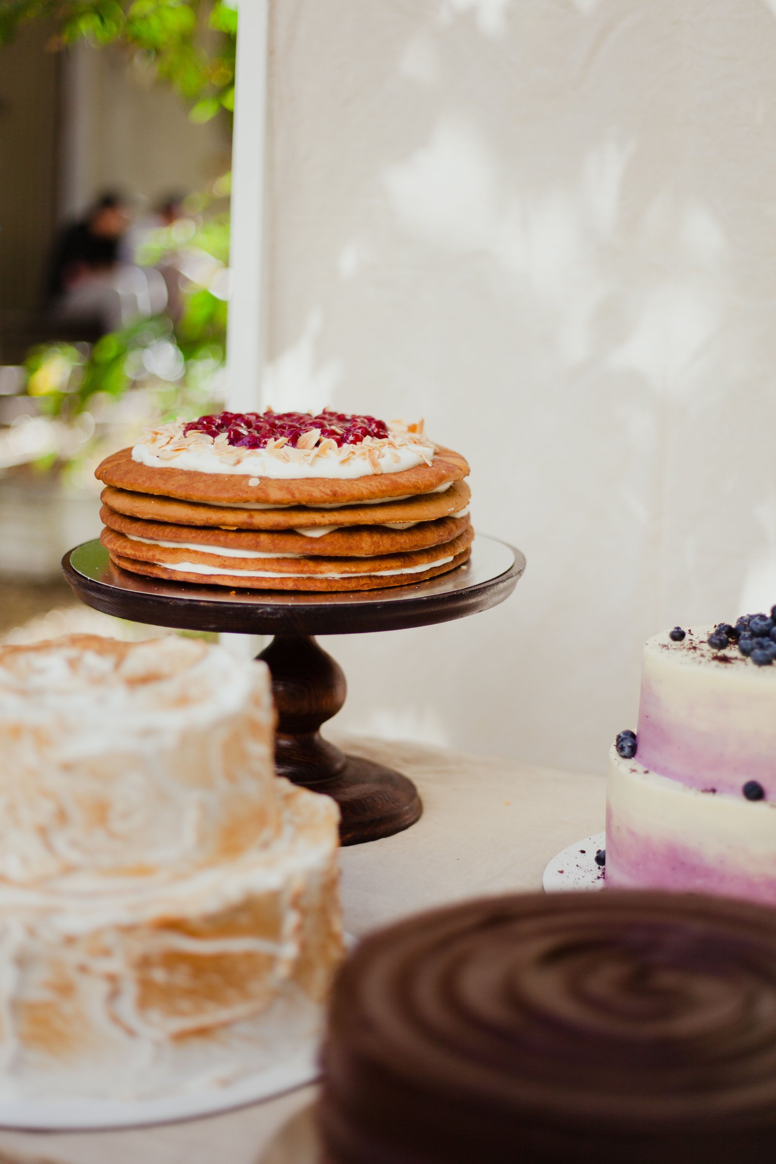 Layered cake with cream and berries on a wooden cake stand